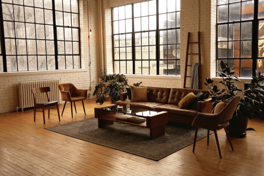 The image features a spacious, contemporary loft living room. The room exhibits an open-concept design, characteristic of loft living, with high ceilings and a minimalist aesthetic.